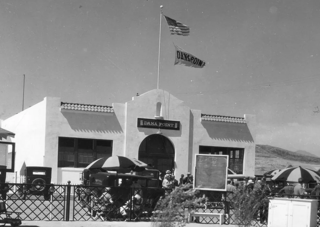 Historic photo of the Woodruff auditorium, a Spanish-style building with flags flying and people out front